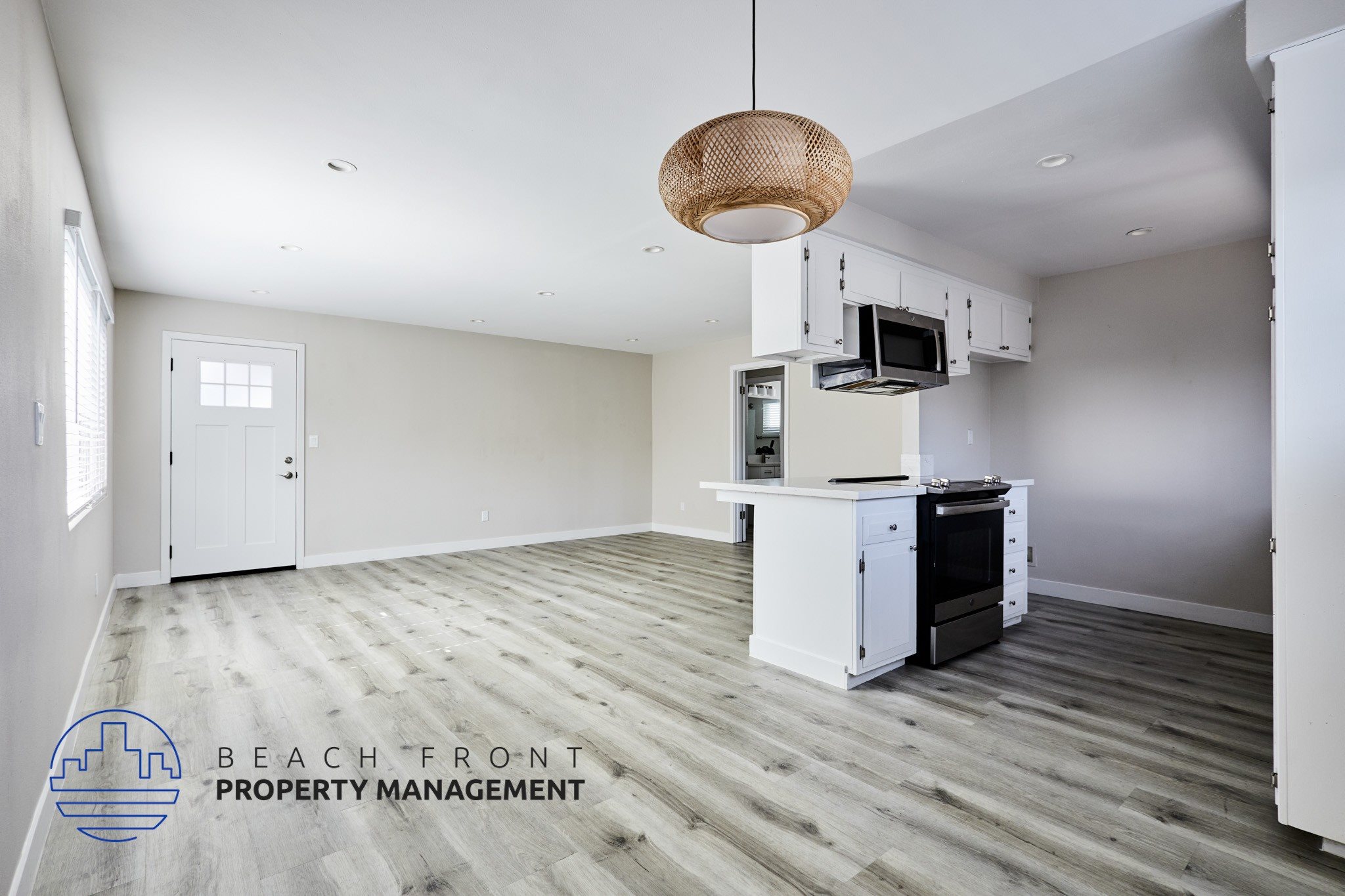 A spacious kitchen and living room with a wooden floor and white walls.